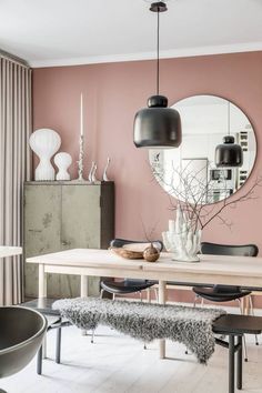 a dining room with pink walls and black chairs in front of a mirror on the wall