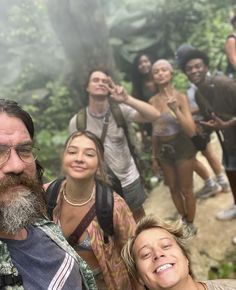 a group of people standing next to each other on a forest trail in the woods