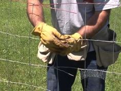 a man is standing in front of a wire fence with his hands on the glove