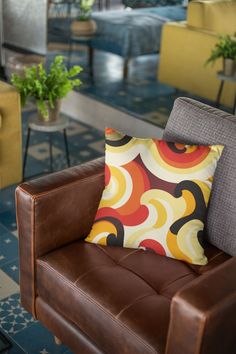 a brown leather chair with a colorful pillow on it