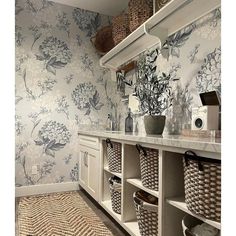 a bathroom with floral wallpaper and baskets on the shelves in front of the sink