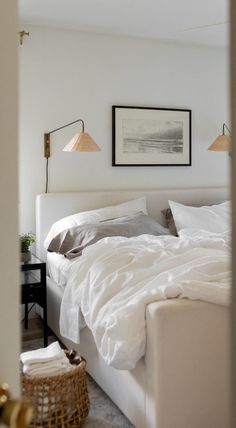 a white bed sitting in a bedroom next to a lamp and pictures on the wall