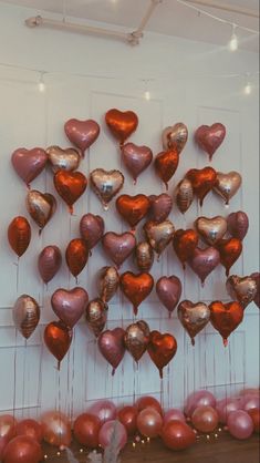 many heart shaped balloons are hanging on the wall