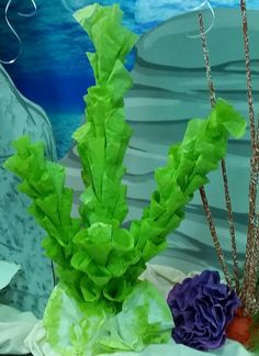 some flowers and plants are on display in front of a rock formation with blue water