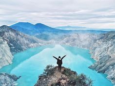 a person standing on top of a mountain with their arms in the air