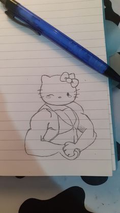 a drawing of a hello kitty sitting on top of a notebook next to a blue pen