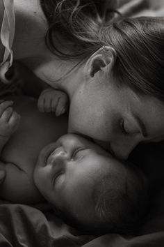 a woman is laying down with her baby