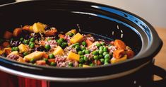 a crock pot filled with rice, peas and carrots