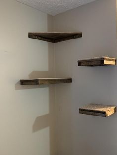 three wooden shelves in the corner of a room