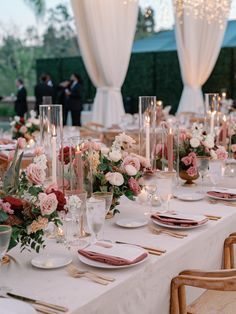 the table is set with flowers, candles and place settings for an elegant dinner party