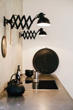 a kitchen with a sink, stove top and hanging lights on the wall above it