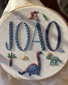 a close up of a embroidery on a piece of cloth with the word aoo written in it