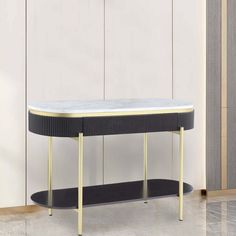 a black and white console table with gold trimmings on the top, in front of a beige wall