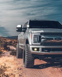 a silver truck driving down a dirt road