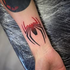 a black and red spider tattoo on the wrist