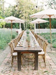 a long table set up with chairs and an umbrella over it for the guests to sit at