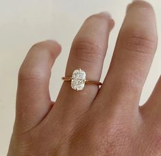 a woman's hand with a diamond ring on top of her finger, showing the center stone