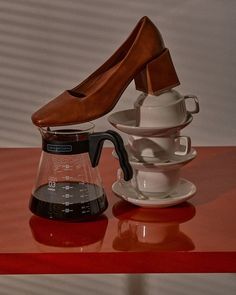 a pair of brown shoes sitting on top of a table next to a coffee pot