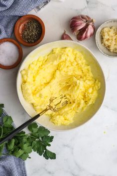 a bowl filled with mashed potatoes next to two small bowls full of chopped parsley