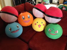 some paper lanterns are sitting on a red couch with other items around them and smiling faces