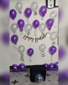 purple and white balloons are hanging on the wall