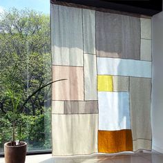 a potted plant sitting next to a window in front of a curtain that has squares on it