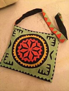 a green and red bag sitting on top of a white table next to a purse