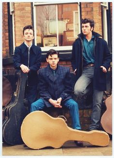 three young men are posing with guitars outside