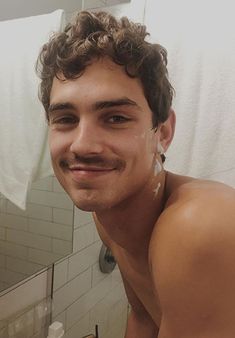 a shirtless man is taking a selfie in front of the bathroom mirror with his moustache