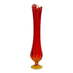 a red glass vase sitting on top of a white table next to a candle holder