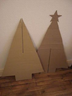 two cardboard christmas trees sitting on top of a wooden floor