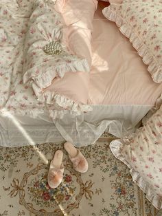 an unmade bed with pink comforter and slippers on the floor next to it