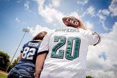 two people wearing football jerseys and facing each other with the sky in the background,