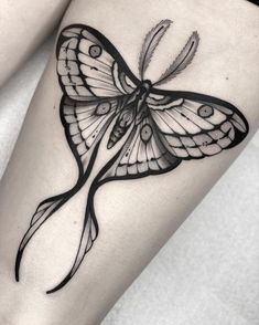 a black and white butterfly tattoo on the right side of the leg, with an intricate design