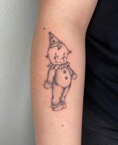 a small tattoo on the arm of a person wearing a hat and holding a teddy bear