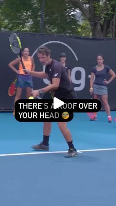 a man holding a tennis racquet on top of a tennis court with people standing behind him