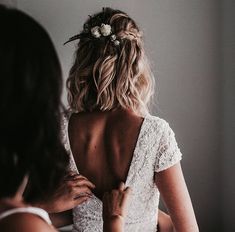 the back of a bride's dress as she fixes her hair