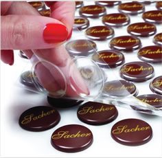 a woman's hand picking up some chocolates from a box with the word schoer on it