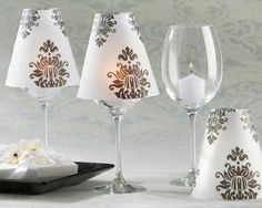 three wine glasses are sitting next to each other with candle holders on the side and napkins in front of them