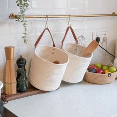 two baskets with wooden spoons and whisk in them on a kitchen counter