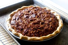 a pecan pie sitting on top of a metal pan next to a cooling rack