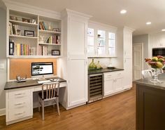 a home office with white cabinets and black counter tops, along with a computer on the desk