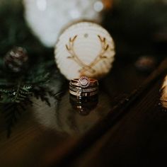 two wedding rings sitting on top of a table next to pine cones and evergreen branches