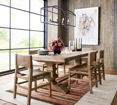 a dining room table and chairs in front of a large window with wood paneling