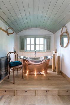 a bathroom with a copper bathtub and chair