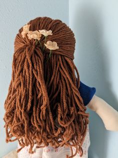 a doll with dreadlocks and flowers in her hair is shown from the back