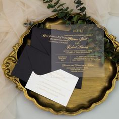 an elegant black and gold wedding suite on a golden plate with greenery around it