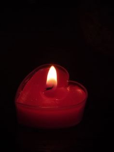 a lit candle in the shape of a heart