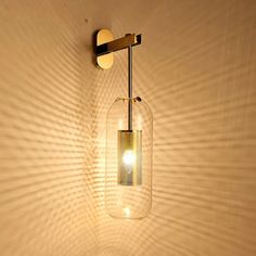 a light that is on the side of a wall next to a glass vase with a candle in it