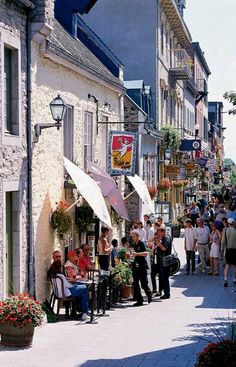 many people are walking down the street in front of shops